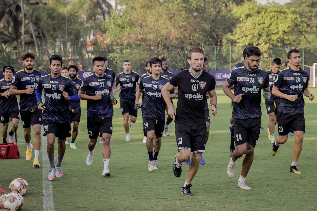 Squadra di calcio in allenamento, dimostrando la loro resistenza nel calcio. I giocatori corrono sull'erba verde, indossando divise blu e nere con sponsor.