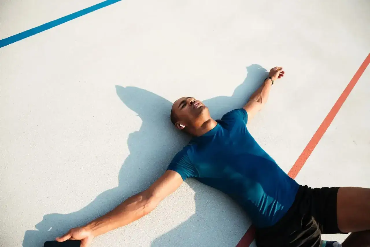 Atleta esausto a terra, con le braccia aperte, forse un esempio di overtraining significato.
