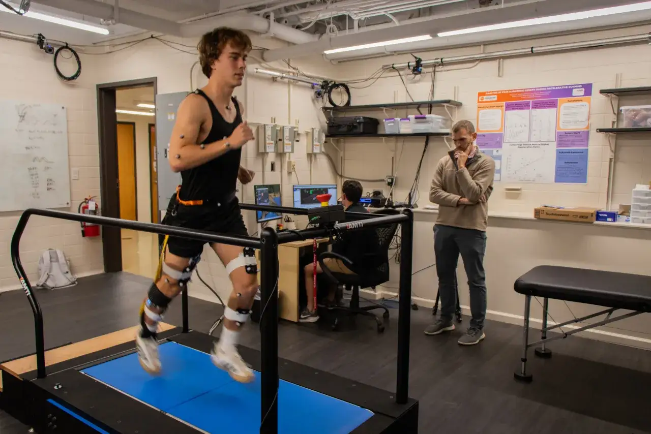 Atleta con marcatori per analisi movimento corre su tapis roulant, studio su lesione hamstring.